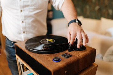 Hand lowering tonearm on vinyl record player, cozy home audio setup