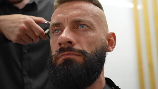 A man is getting a trendy haircut at a barbershop. The barber carefully trims the hair using clippers, focusing on creating a clean and stylish look