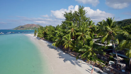 Luxury resort photo of Seychelles tropical paradise islands
in Indian Ocean with palm trees, sandy beach, house. Beautiful photography, coral reef, azure ocean, mountain on horizon. 