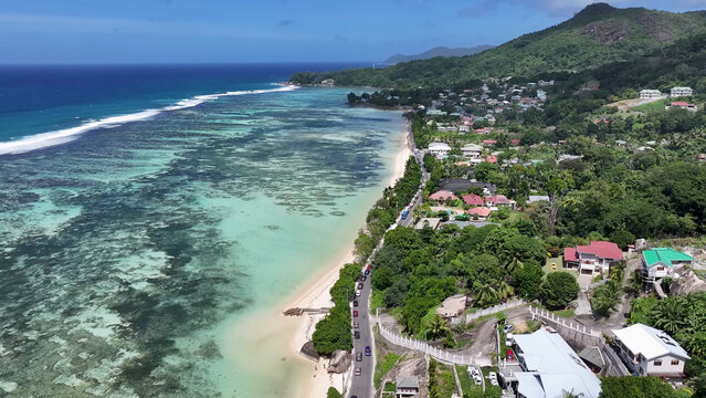 Luxury resort photo of Seychelles tropical paradise islands
in Indian Ocean with palm trees, sandy beach, house. Beautiful photography, coral reef, azure ocean, mountain on horizon. 