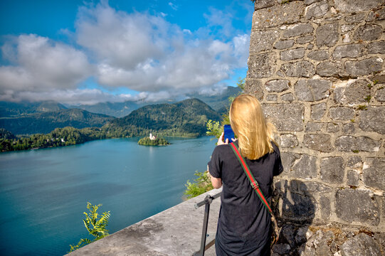 Lake Bled, Slovenia – July 22, 2025: A visitor photographs the iconic Bled Island and surrounding Alps from the medieval Bled Castle viewpoint.