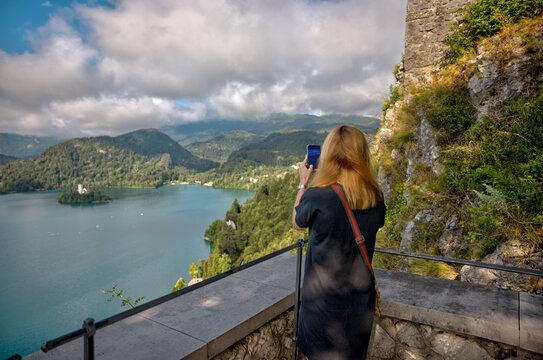 Lake Bled, Slovenia – July 22, 2025: A visitor photographs the iconic Bled Island and surrounding Alps from the medieval Bled Castle viewpoint.