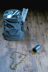 A backpack, heavy with canned provisions. Scattered green peas, forming the distinctive outline of South America, spill from an overturned can, illustrating dreams bigger than the budget.