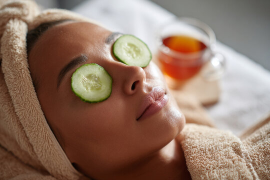 Relaxing spa experience with cucumber slices on eyes while enjoying herbal tea