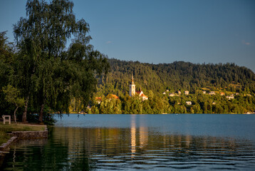 Obraz premium Lake Bled, Slovenia – July 22, 2025: Scenic views of Bled Island and its iconic Church of the Assumption surrounded by the Julian Alps and crystal waters. 