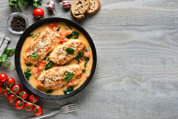 Chicken breast in creamy sauce with tomatoes and spinach on plate