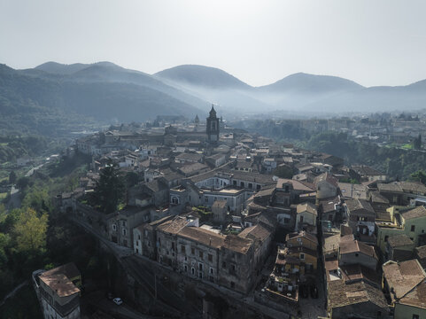 Aerial view of ancient rooftops cascade under the watchful gaze of the bell tower, nestled amidst rolling hills and bathed in the soft light, Sant Agata de Goti, Campania, Italy.
