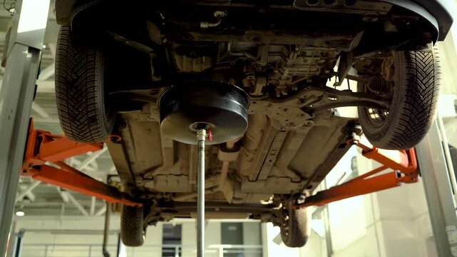 The car is lifted onto a lift at a service station to drain the used oil