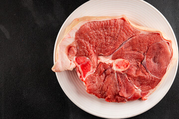 Bone-in ham steak, raw pork ham on the bone tasty snack fresh gourmet food background on the table  rustic food top view copy space