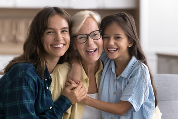 Preteen girl adult daughter hugging elderly mom from both sides