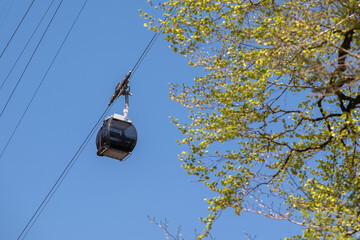A cable car hangs in the air with a backdrop of blue sky and lush natural scenery. Peaceful outdoor landscape perfect for travel, adventure, and nature photography.