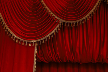 Rich red velvet curtains with ornate golden trim in a theater setting during a performance