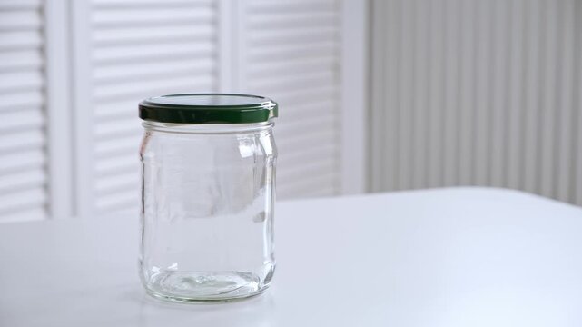 A man screws a metal lid onto an empty glass jar. Air conservation. The concept of nonsense. Reusable tableware for storage. Environmentally friendly material. High quality 4K footage.