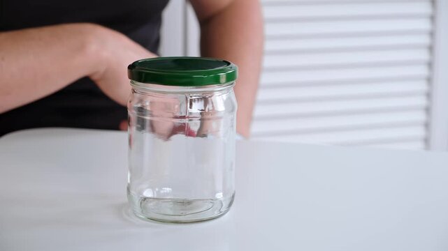 A man screws a metal lid onto an empty glass jar. Air conservation. The concept of nonsense. Reusable tableware for storage. Environmentally friendly material. High quality 4K footage.
