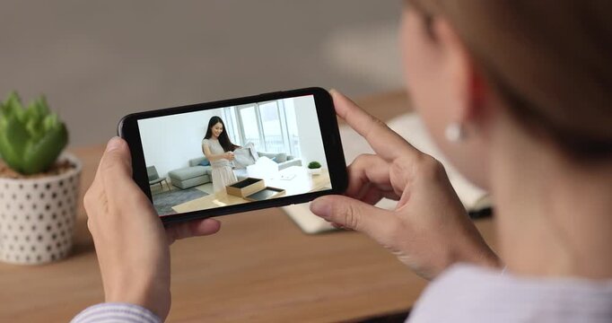 Woman watching unpacking videovlog on smartphone, close up