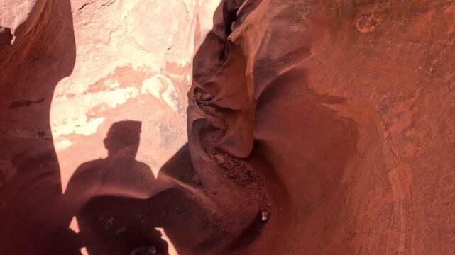 POV walking shot of extremely narrow twisting passage with textured sandstone walls in Peekaboo Slot Canyon