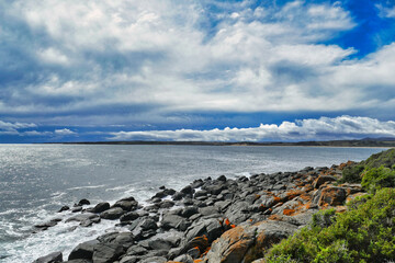 Rocky coast with lichen covered boulders under a cloudy sky at Low Head, George Town, in the Launceston region of  northern Tasmania, Australia.  
