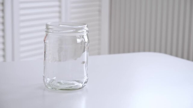 An empty glass jar without lid. Reusable container for canning and storing food. Concepts of reusable tableware for storage. Environmentally friendly material. High quality 4K footage.
