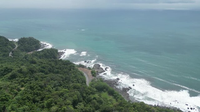 Aerial view of a coastline and turquoise sea with rocks and reefs near the Jaco Beach viewpoint in Puntarenas in Costa Rica