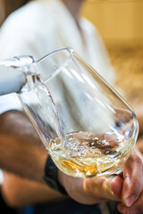 Pouring refreshing white wine into clear glass