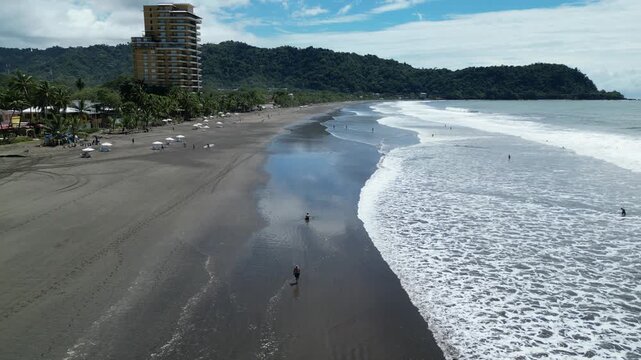 Aerial view of waves near the beach town of Jaco with tourist and hotel buildings and businesses in the province of Puntarenas in Costa Rica