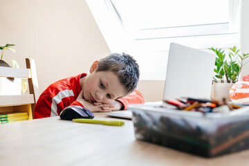 Boy feeling bored studying online with laptop