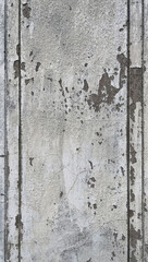 Close-up of a weathered concrete wall with peeling paint and vertical grooves, showing rough texture, cracks, and signs of aging.