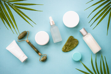 Natural cosmetic product with palm leaves on blue background.