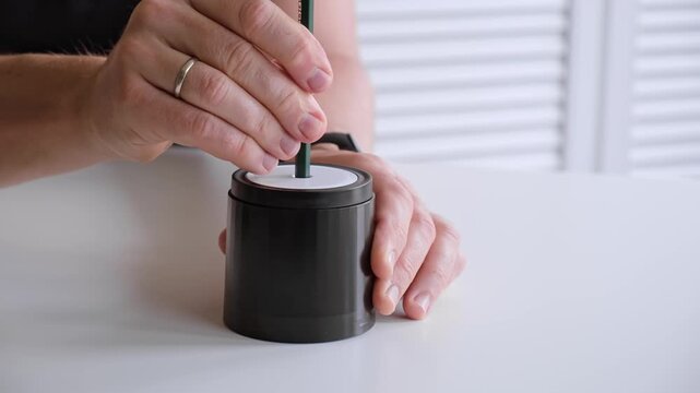 Male hand sticking pencil into automatic electric pencil sharpener and sharpening it close-up side view. Office stationery tool. Preparation for drawing and sketching. High quality 4k footage.