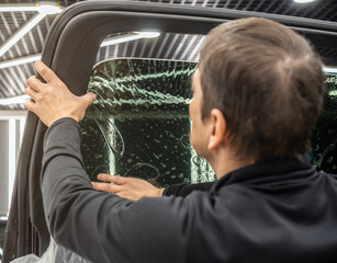 Male car service worker glue window tinting in luxury car detailing car repair the concept of love...