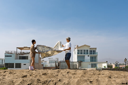 Young couple preparing beach blanket for relaxation