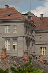 corner of historic building with red roof and chimneys, layered windows and textured walls convey old town