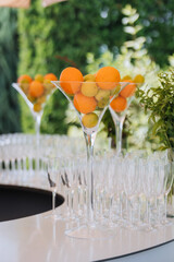 Tall martini centerpiece with citrus above rows of champagne flutes at an outdoor bar
