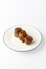 Beef roulade slices with rich gravy on white plate, isolated studio food photo