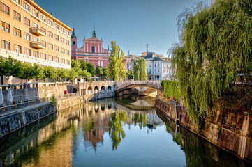 Ljubljana, Slovenia – July 14, 2025: A scenic view of the Ljubljanica River as it winds through the historic center of Ljubljana. Lined with trees, cafés, and charming riverside architecture.
