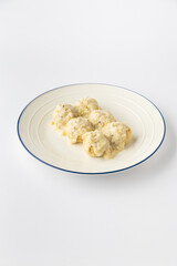 Creamy mustard meatballs on a plate, studio food shot on white background