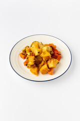Roasted vegetable medley on plate: golden potatoes, carrots, peppers, zucchini, studio isolated