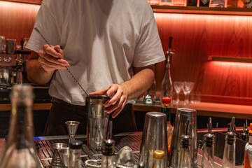 Bartender mixing cocktail with shaker at stylish bar counter
