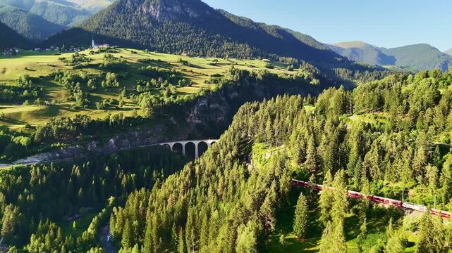 red swiss train on Landwasser viaduct bridge in Swiss Alps. Zermatt to St. Moritz.  scenic railway. Switzerland summer tourism.