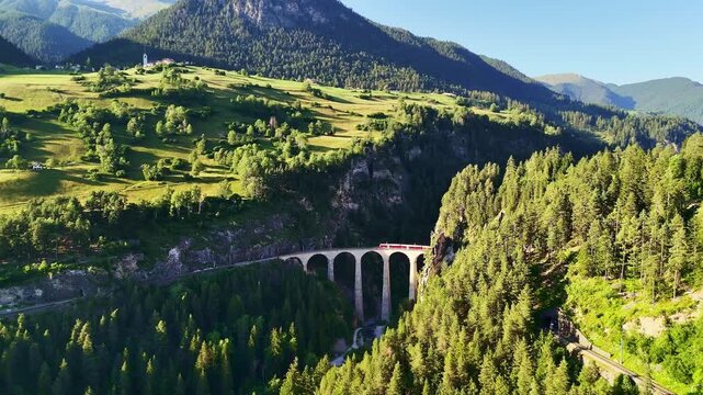 red swiss train on Landwasser viaduct bridge in Swiss Alps. Zermatt to St. Moritz.  scenic railway. Switzerland summer tourism.