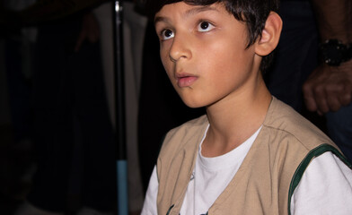 Portrait of a Hispanic boy wearing a vest, focused and looking upwards during a science and technology fair in Neiva, Huila, Colombia. Concept of Colombian people