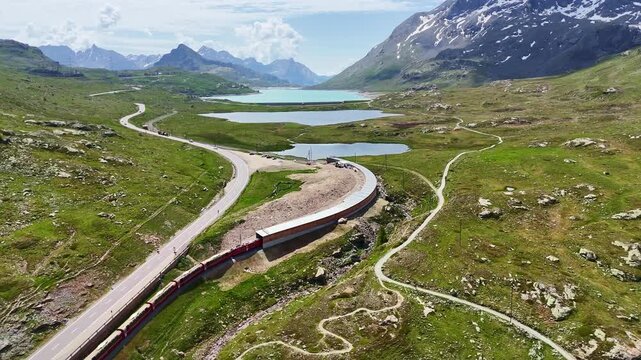 red swiss train in Swiss Alps. Rhaetian Railway famous Lake Bianco on way to St. Moritz. Switzerland summer tourism.