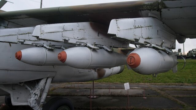 closeup view of military aircraft wing with prepared missile launchers and ground crew activity
