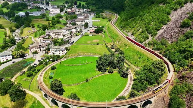 Drone Switzerland 4k.  train on way to St. Moritz. Brusio spiral viaduct, stone spiral railway viaduct on the Bernina Railway. Swiss Alps in summer. 
