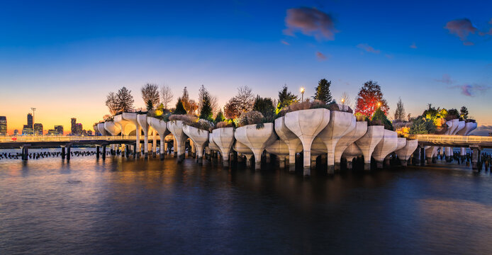 Little Island at Pier 55 silhouetted against a sunset cityscape in New York, USA