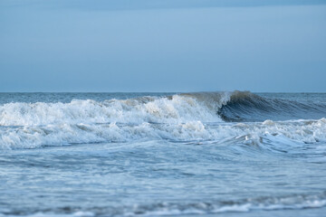 Waves gently roll onto the shore under a clear sky during early morning at a serene beach location
