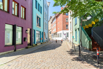 Colourful houses and apartment buildings along a cobbled pedestrian street in a city centre on a sunny summer day