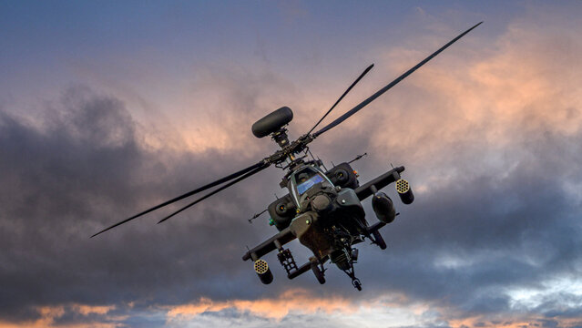 Modern military attack helicopter in flight at dusk.