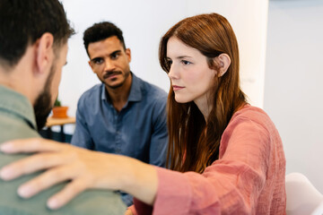 Colleagues offering emotional support during group session. People comforting stressed coworker. Mental health and wellbeing concept.