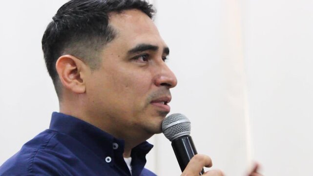 Portrait of a Latino male teacher speaking into a microphone inside a science and technology classroom in Neiva, Huila, Colombia. Concept of education and discourse